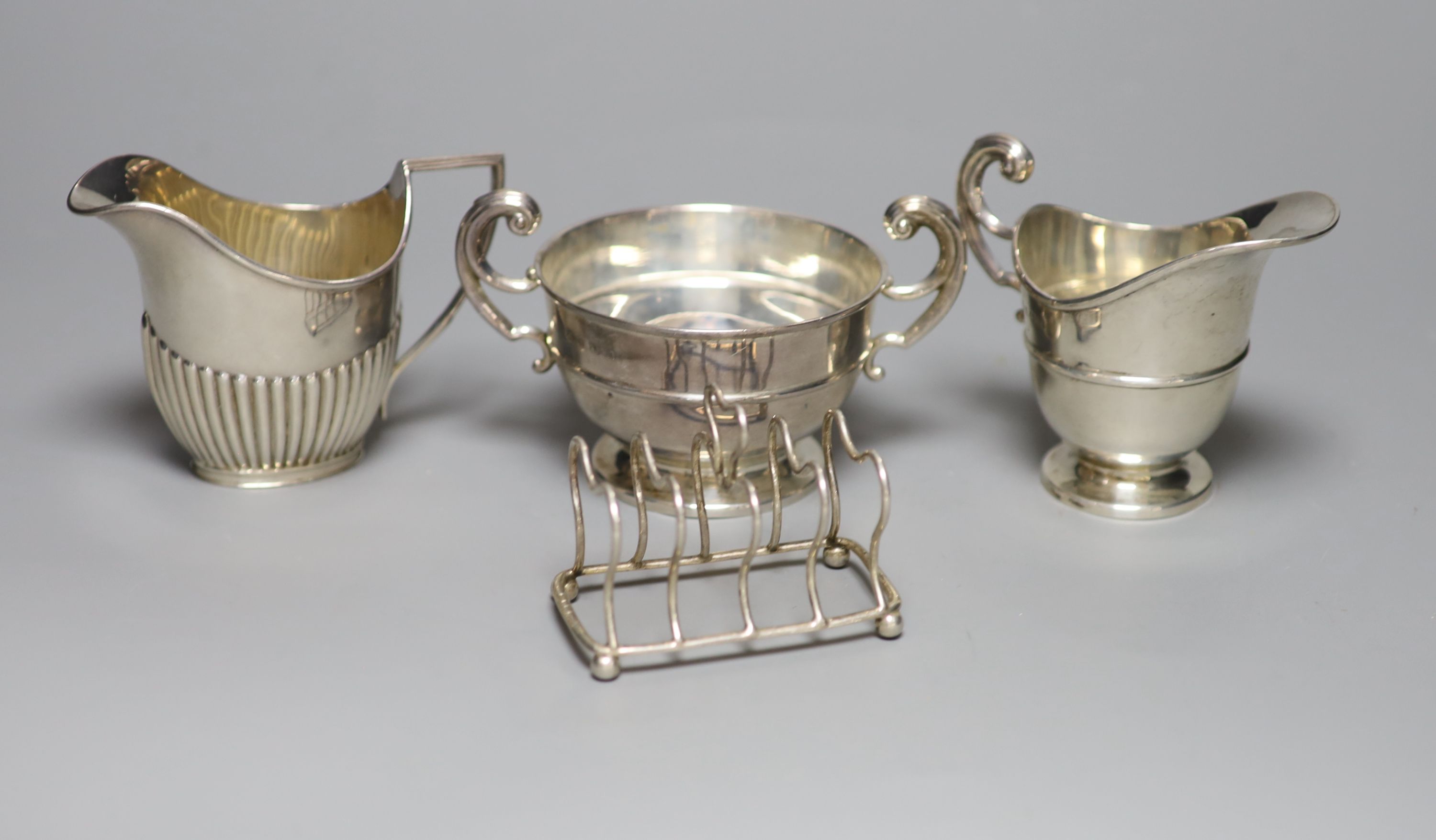 An Edwardian silver cream jug and sugar bowl, Birmingham, 1909, a demi fluted silver cream jug and a silver toastrack